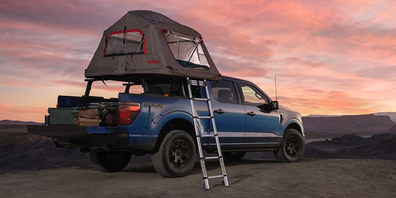 2025 Ford F-150 parked outdoors with a rooftop tent setup at sunset, showcasing its off-road capability and adventure-ready design.