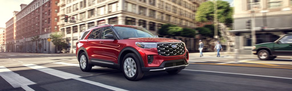 A red 2025 Ford Explorer drives through a city near Winchester, MA